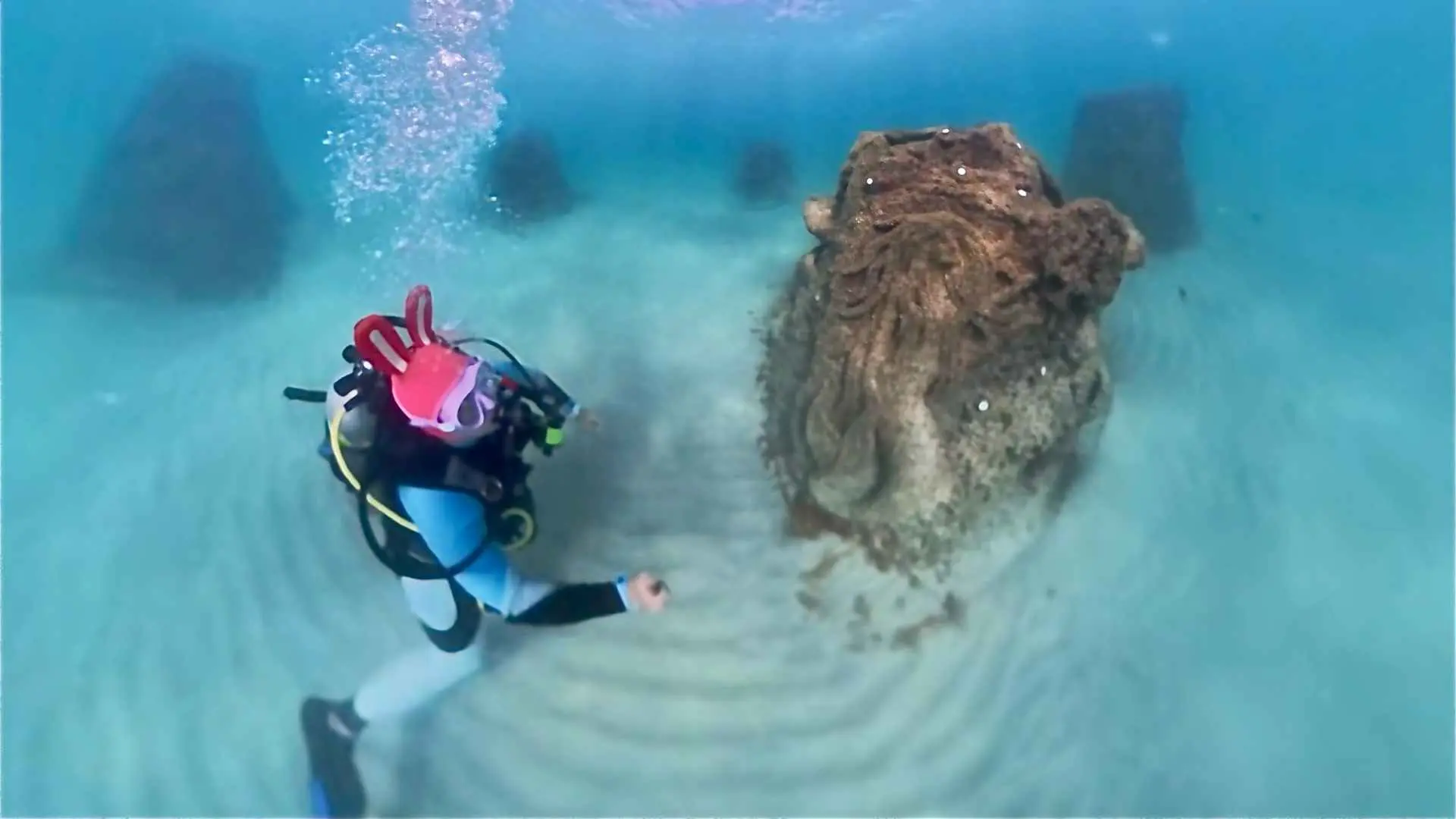 Scuba diver explores multiple reef modules on the ocean floor off Hollywood Beach, Florida under bright sunlight